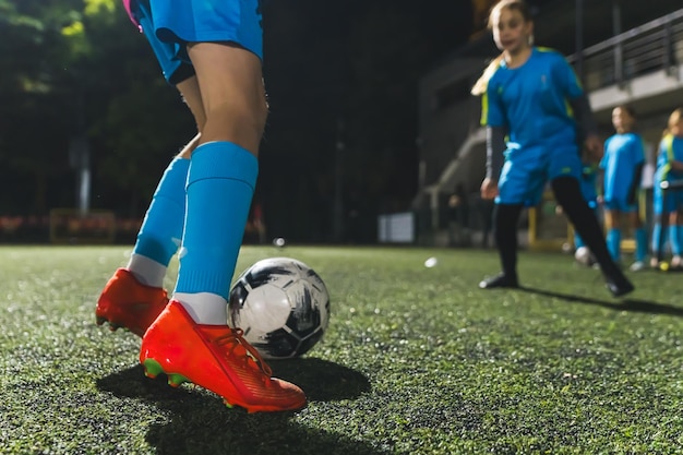 Photo closeup shot of a girl playing with a soccer ball in a stadium evening practice blue uniforms