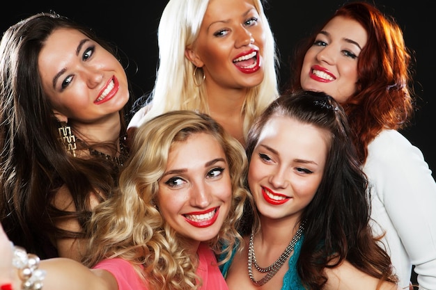 Closeup shot of group of laughing girls having party take selfie with smartphone