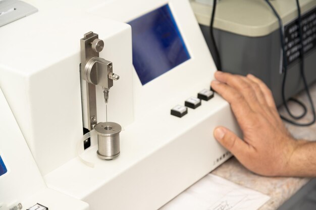 A closeup shot of a hand using a medical machine to test and manufacture pharmaceutical syringes