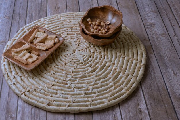 Closeup shot of hazelnuts and biscuits in wooden bowls on a cork trivet