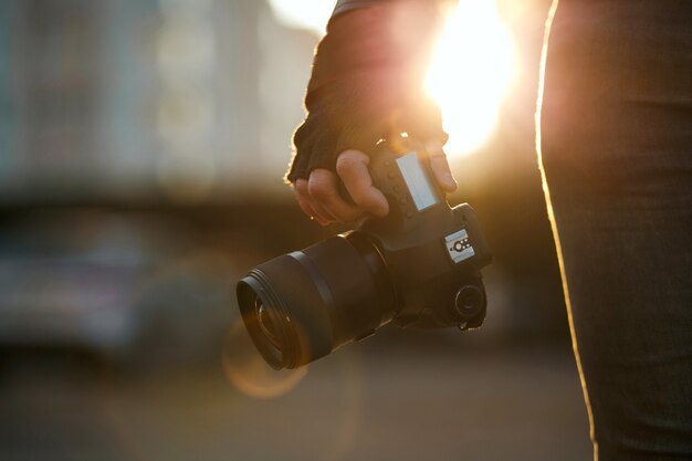 Closeup shot of a man in gloves holding digital camera against the sun light. Copy space