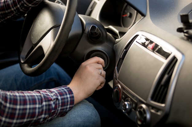 Closeup shot of man inserting key in car ignition lock