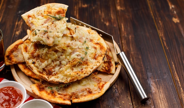 Closeup shot multiple stack hot oven baked tasty delicious Italian homemade ham pineapple traditional Hawaiian bread crust pizzas on wood plate serving with tomato ketchup and herbs with soft drink