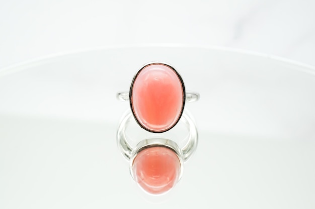 Closeup shot of a pink oval opal ring on a white surface