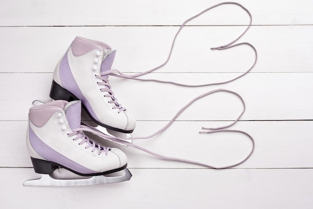 Closeup shot of professional ice skates lying on a white wooden background Laces are in the form of hearts The concept of sports recreation leisure