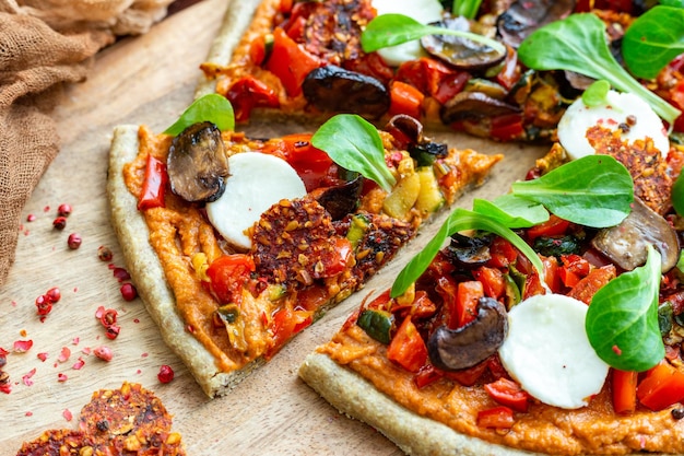 Closeup shot of raw vegan fresh pizza with mushrooms and other vegetables served on a wooden board