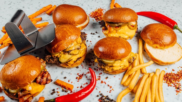 Closeup shot of tasty smash burgers, French fries, and red spicy pepper on the white background