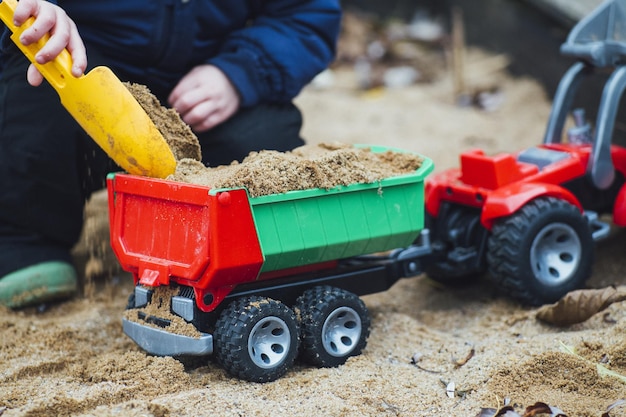 Closeup shot of a toddler playing with sand and construction toys in the park during daytime