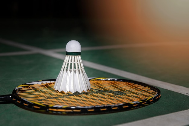 Closeup shot of white badminton shuttlecock and racquet on green floor