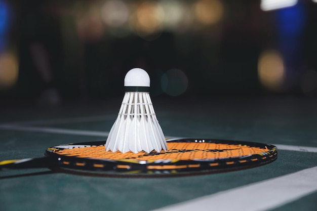 Closeup shot of white badminton shuttlecock and racquet on green floor