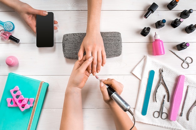 Closeup shot of a woman in a nail salon receiving a manicure by a beautician with nail file woman ge...