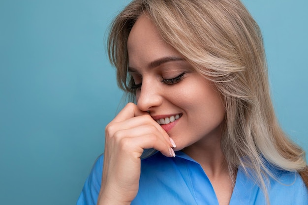 Closeup of shy cute casual young woman looking away against bright blue background