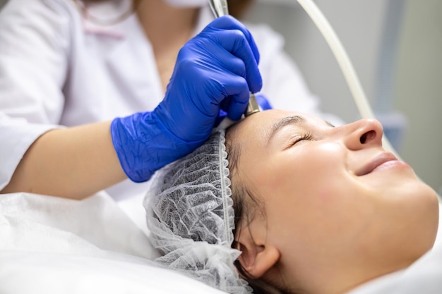 Photo closeup side shot of a beautiful young woman on a facial derma pen microneedling treatment at the beauty salon