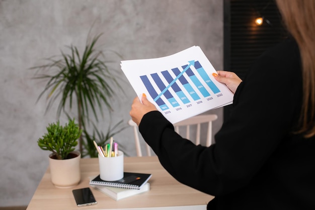 Closeup side view of woman hand holding analyzing graphs and diagrams statistic growing graphic