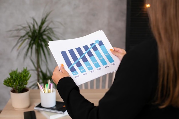 Closeup side view of woman hand holding analyzing graphs and diagrams, statistic, growing graphic.