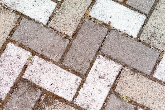 Closeup of sidewalk paved with rectangular white and gray tiles in top view