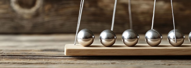 Photo closeup of silver balls suspended on a wooden base