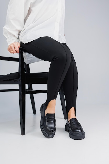 Closeup of slender female legs in black leggings and black leather loafers New springsummer collection of women's leather shoes