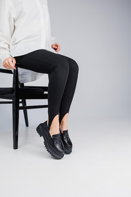 Closeup of slender female legs in black leggings and black leather loafers New springsummer collection of women's leather shoes