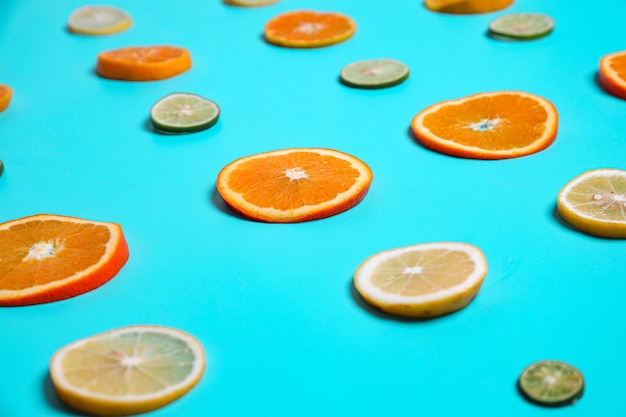 Closeup of sliced lemons limes and orange fruits in row set on blue background