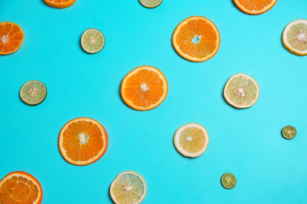 Closeup of sliced lemons limes and orange fruits in row set on blue background