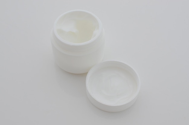 Closeup of a small pot of white cream symbolizing aesthetic care and the quest for perfect skin