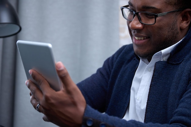 Closeup of a smiling African entrepreneur with glasses using a digital tablet