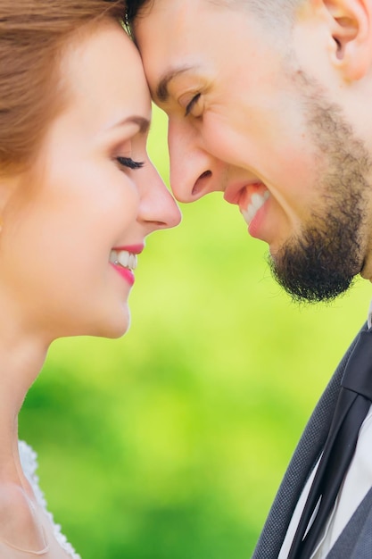 Closeup of smiling newlyweds against the backdrop of greenery