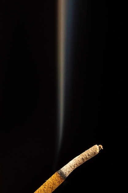 Closeup of smoking stick of incense isolated on a black background