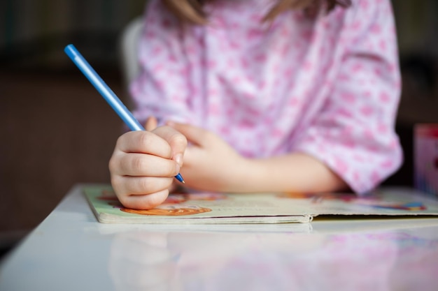 Closeup soft focus on hands little girl as she writes letter and notepad on a table