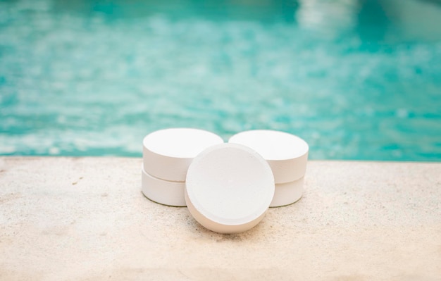 Closeup of some chlorine tablets for cleaning on the edge of a swimming pool chlorine tablets to clean swimming pools concept of chlorine tablets to disinfect swimming pools