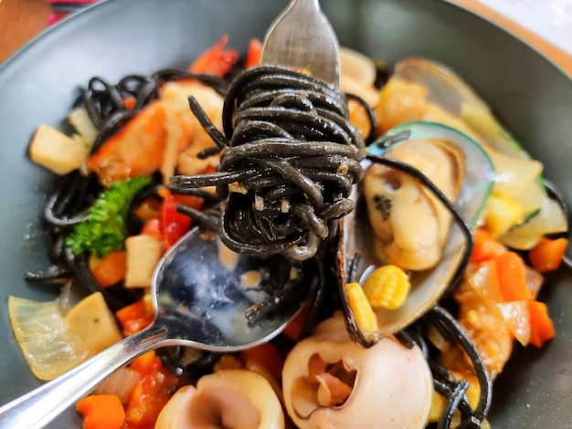 Closeup the spaghetti black squid with seafood such as prawn calamari mussel and vegetables