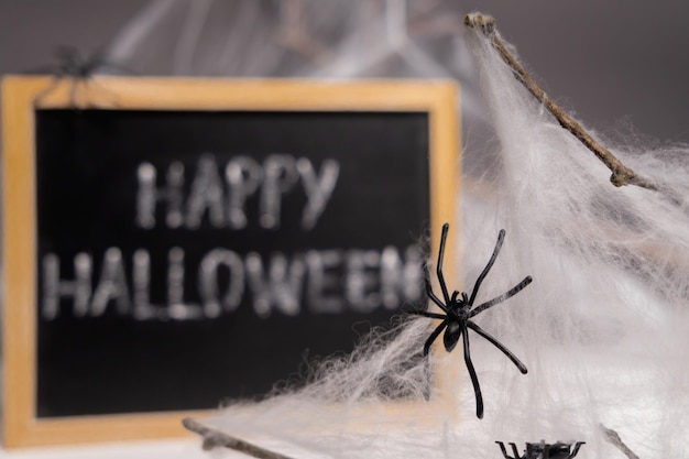 Photo closeup of spiders in a web against the background of a board with the inscription happy halloween