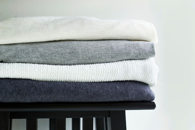 Closeup stack of folded monochrome clothes on white background wall