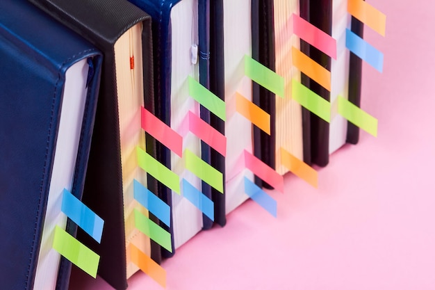 Closeup of a stack of office notepads with colorful sticky page markers sandwiched between pages