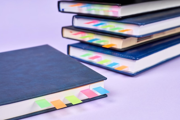 Closeup of a stack of office notepads with colorful sticky page markers sandwiched between pages