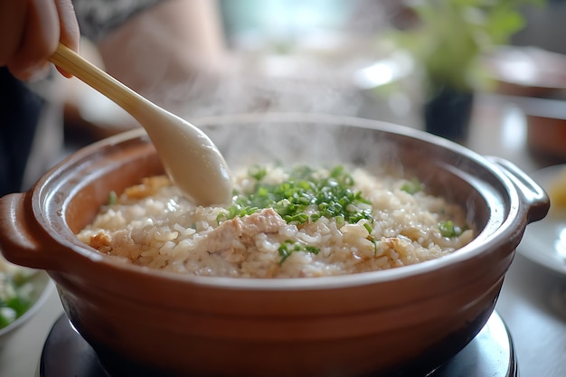 Closeup of a steaming bowl of rice with green onions and a wooden spoon