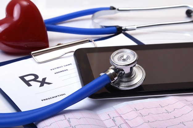 Closeup of stethoscope on a rx prescription, red heart and phone isolated on white background.