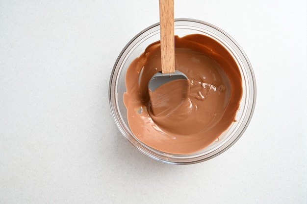 Closeup stirring milk melted chocolate in glass bowl isolated on white Candy making pastry production dessert concept