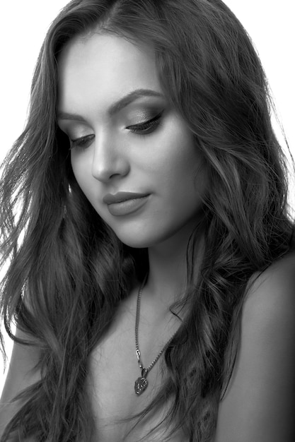 Closeup studio portrait of a sad woman with curly hair and natural makeup. Black and white shot