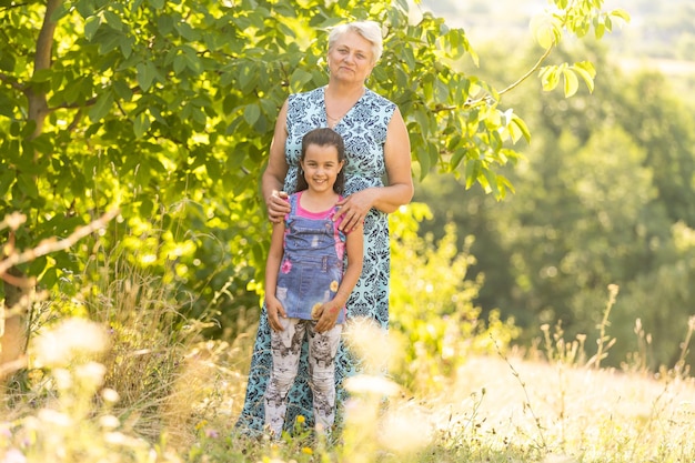 Closeup summer portrait of happy grandmother with granddaughter outdoors.