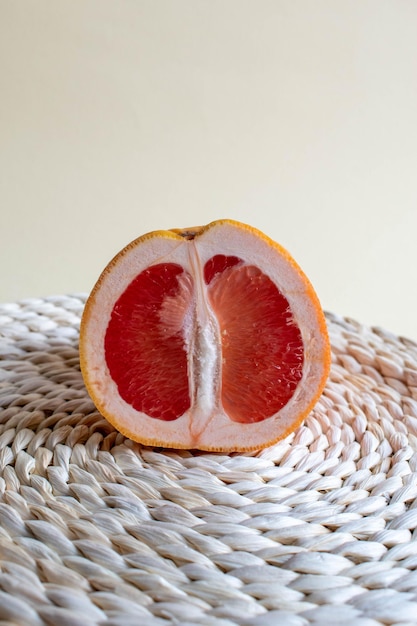 Closeup summer still life with two cut grapefruits on a sandy background with a straw stand Space for text