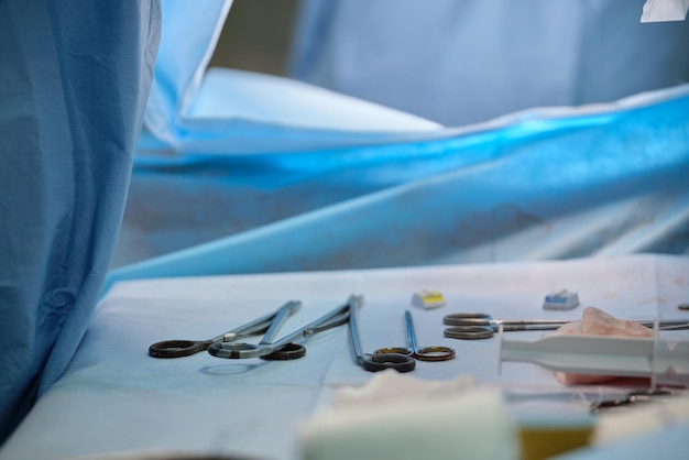 Closeup of surgical tools on table and team of surgery doctors operating a patient in hospital room