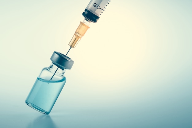 Closeup of syringe and flu vaccine injection, measles or hpv vaccine on vintage medical background