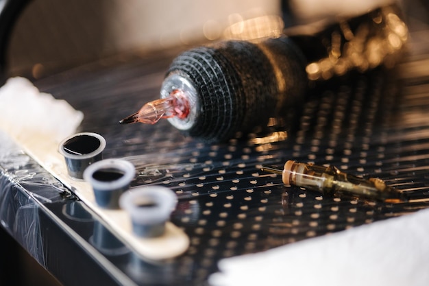 Closeup of tattoo machine in studio professionnal wireless tatto machine and little cups with ink