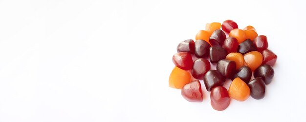 Closeup texture of red orange and purple multivitamin gummies on white background healthy lifestyle