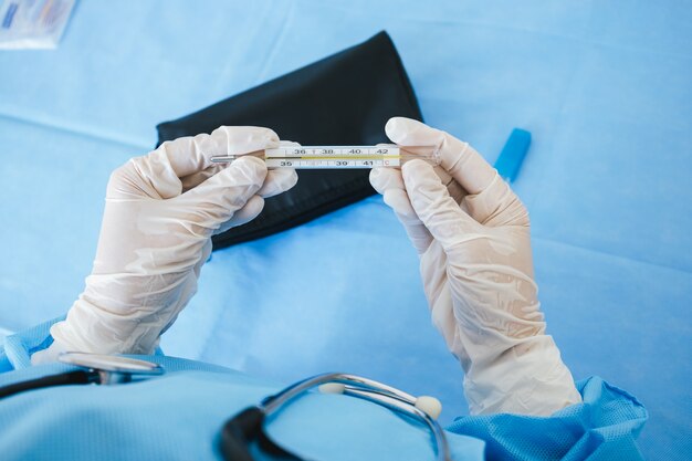 Closeup of thermometer in the hand of medical worker.