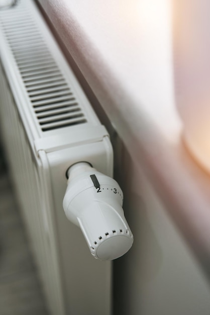 Closeup of a thermostat on the heating radiator Heater regulator in the modern white interior Temperature knob