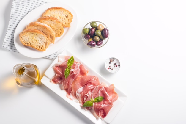 Closeup of thin slices of prosciutto with mixed olives