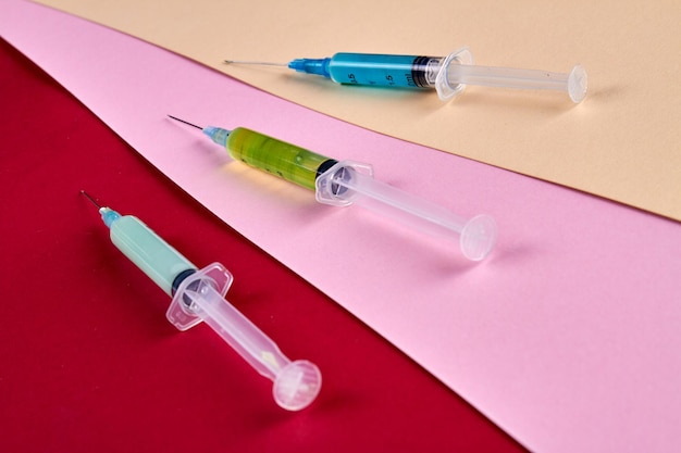 Closeup three syringes filled with multicolored medicine liquids drugs addiction and injections conc